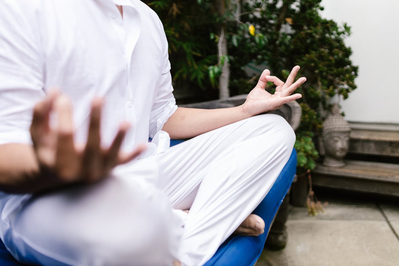 services-04 A person in white practicing yoga meditation outdoors in a serene environment.